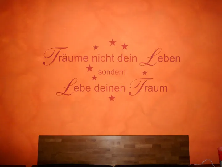 Wandschrift auf Orange: Träume nicht dein Leben, lebe deinen Traum